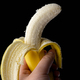 Asian woman&#39;s hand holding a fresh, yellow banana. Isolated on black background. Side view. - PhotoDune Item for Sale