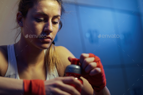 Young sportswoman having water break in a locker room.