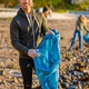 Young man collects garbage in bag with group of volunteers on sunny day - PhotoDune Item for Sale