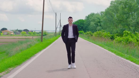 Guy with Elegant Suit Walks on the Road Among the Nature alt