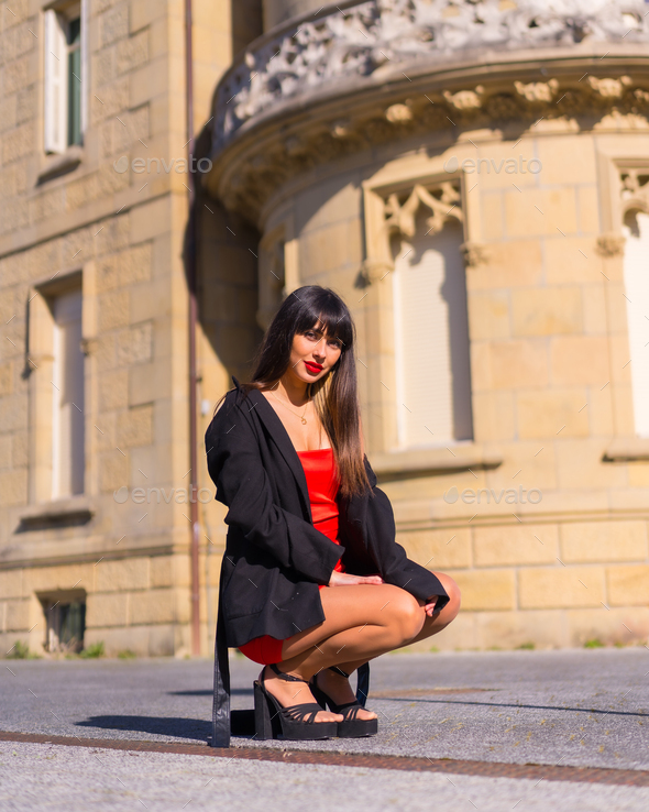 Portrait in red dress in beautiful castle, attractive girl, crouching posed smiling