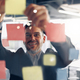 Close up of smiling businessman is glues sticky notes on motivation board in modern office - PhotoDune Item for Sale