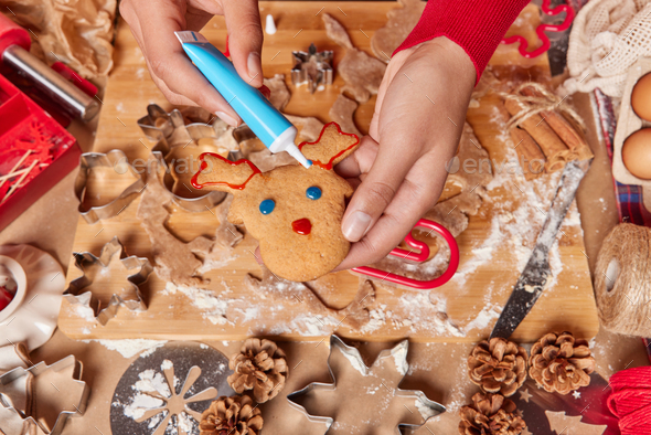 Overhead shot of unrecognizable person decorates reindeer ginger cookie prepares delicious tradition - Stock Photo - Images