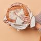 Vertical shot of unrecognizable woman holds round loaf of bread on towel isolated over beige backgro - PhotoDune Item for Sale