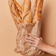 Vertical shot of unknown person holds paper bag of freshly baked baguettes isolated over beige backg - PhotoDune Item for Sale