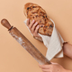 Unrecognizable person holds homemade crusty appetizing bread wrapped in linen napkin and rolling pin - PhotoDune Item for Sale