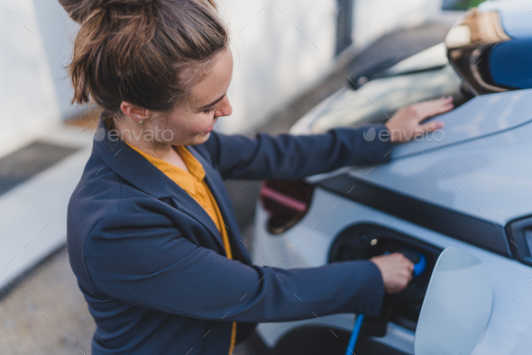 Young woman charging her electric car in home, sustainable and economic transportation concept. - Stock Photo - Images