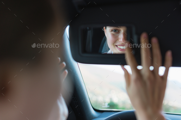 Rear view of young woman in car, looking at rearview mirror. - Stock Photo - Images