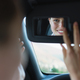 Rear view of young woman in car, looking at rearview mirror. - PhotoDune Item for Sale