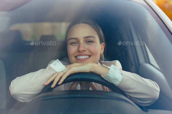 Excited young woman sitting in her car, prepared for driving. - Stock Photo - Images