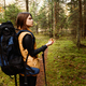European young girl tourist with large backpack walks through forest with compass and walking sticks - PhotoDune Item for Sale