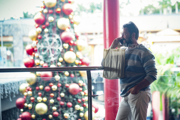 One man doing phone call inside a commercial mall center in christmas december season