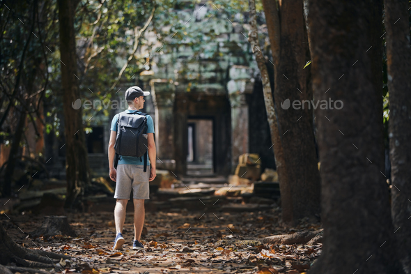 Man with backpack coming to ancient temple - Stock Photo - Images