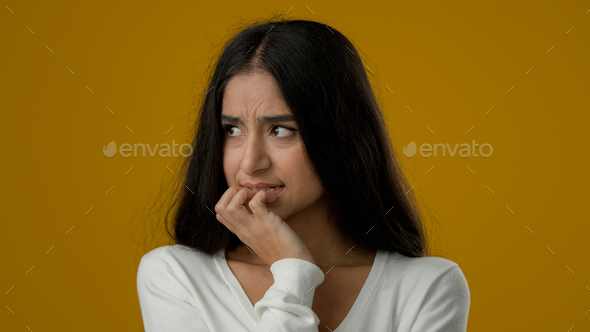 Female portrait isolated sad afraid worried Indian ethnic woman lady girl in studio yellow