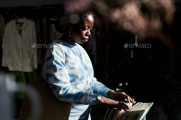 Black young woman choosing vintage records in thrift store