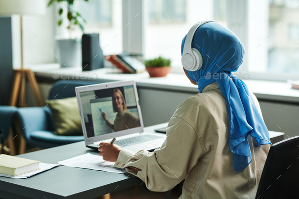 Back view of young Muslim female student during online lesson