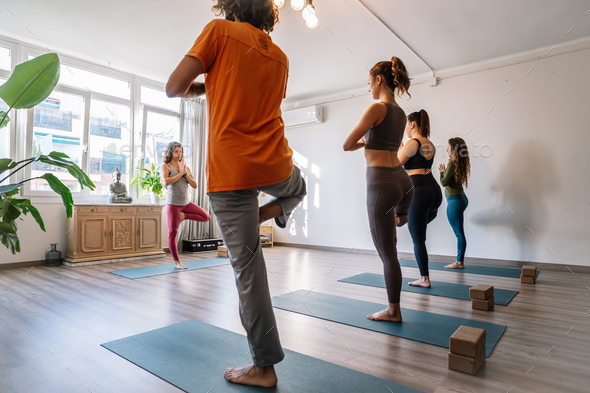 Group repeating Vriksasana pose after coach Stock Photo by guillemd