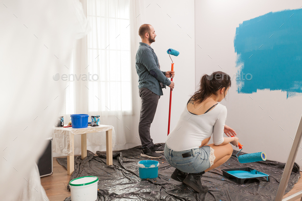 Couple painting apartment wall