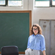 Young woman school teacher standing at desk in front of chalkboard in classroom. - PhotoDune Item for Sale