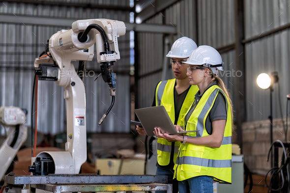 In robotic training instructor teach girl engineer to program robot arm ...