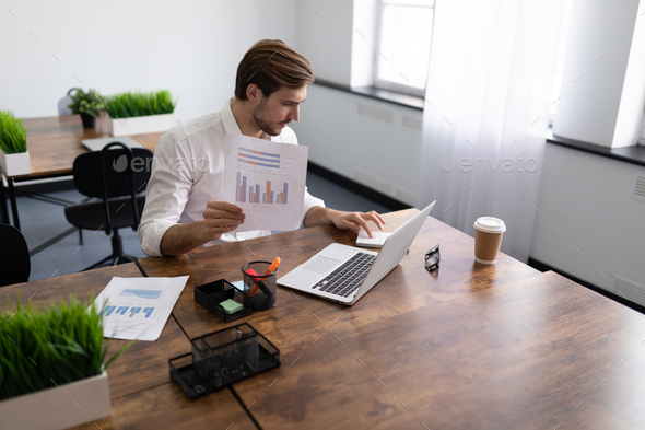 businessman in a stylish office on a laptop calculates the profit and dividends of his enterprise - Stock Photo - Images