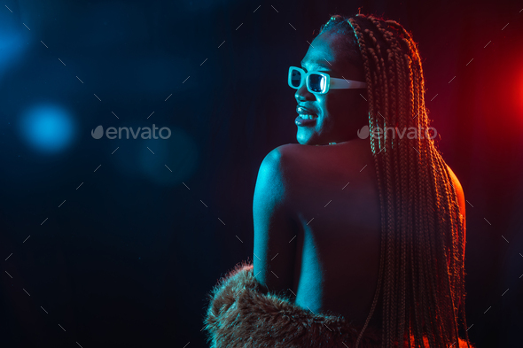Black ethnic woman with braids with blue red led lights, model from the back, sensual pose looking