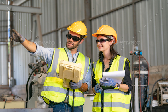 Robotics engineer working on maintenance of modern robotic arm in factory warehouse - Stock Photo - Images