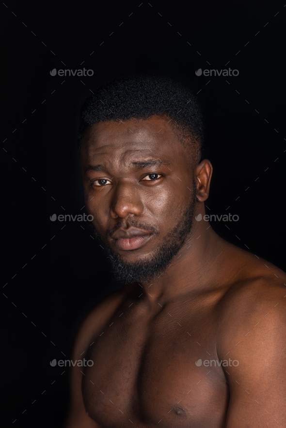 handsome young bare chested african american man looking at camera