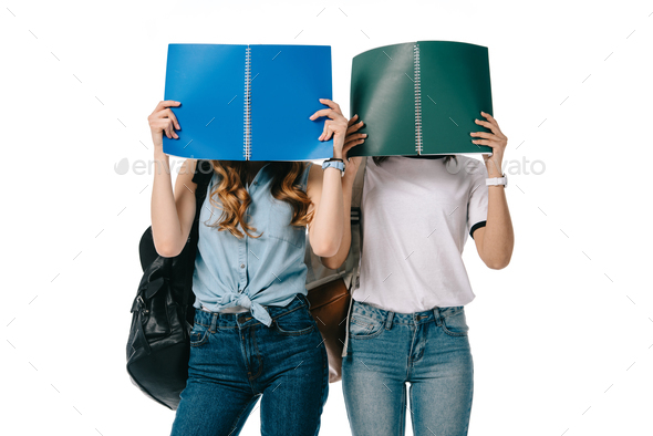 multicultural students covering faces with copybooks isolated on white