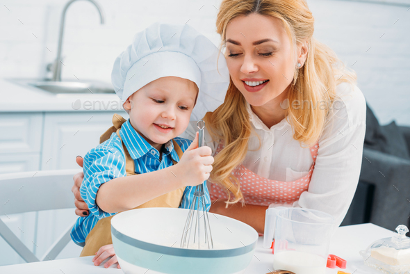 Smiling mother embracing little son while he using hand beater Stock ...