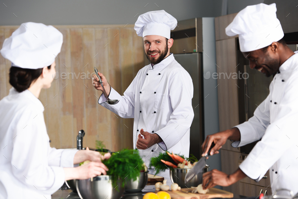 Multiracial chefs team cooking together by kitchen counter