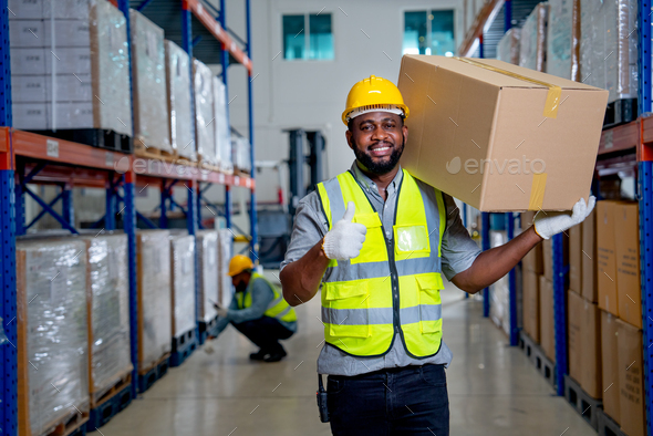 African American warehouse worker carry the box on his shoulder and show thumbs up to camera