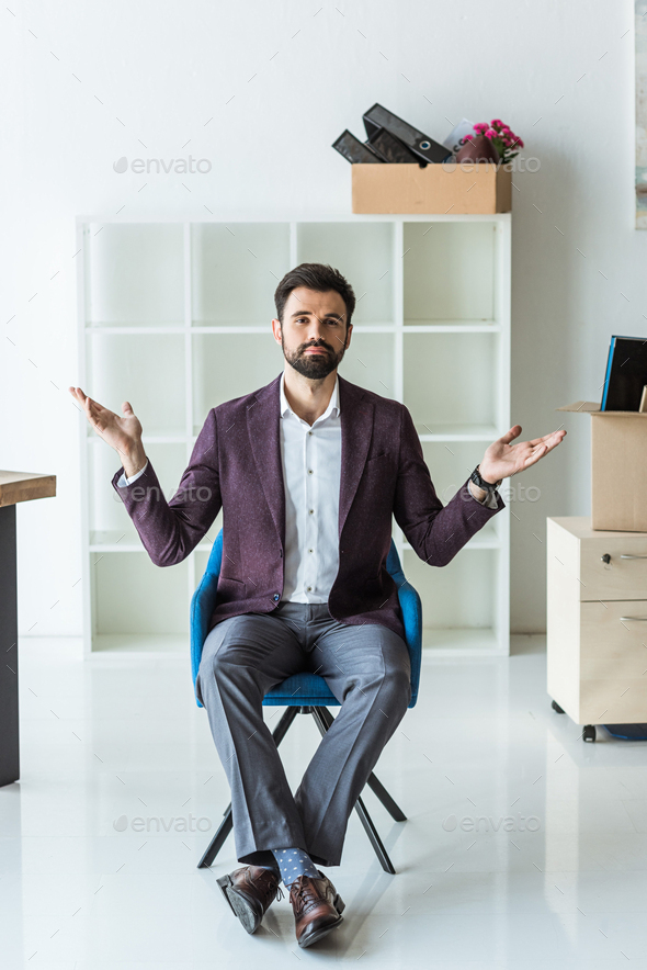 bewildered young businessman sitting on chair in office after he gets fired