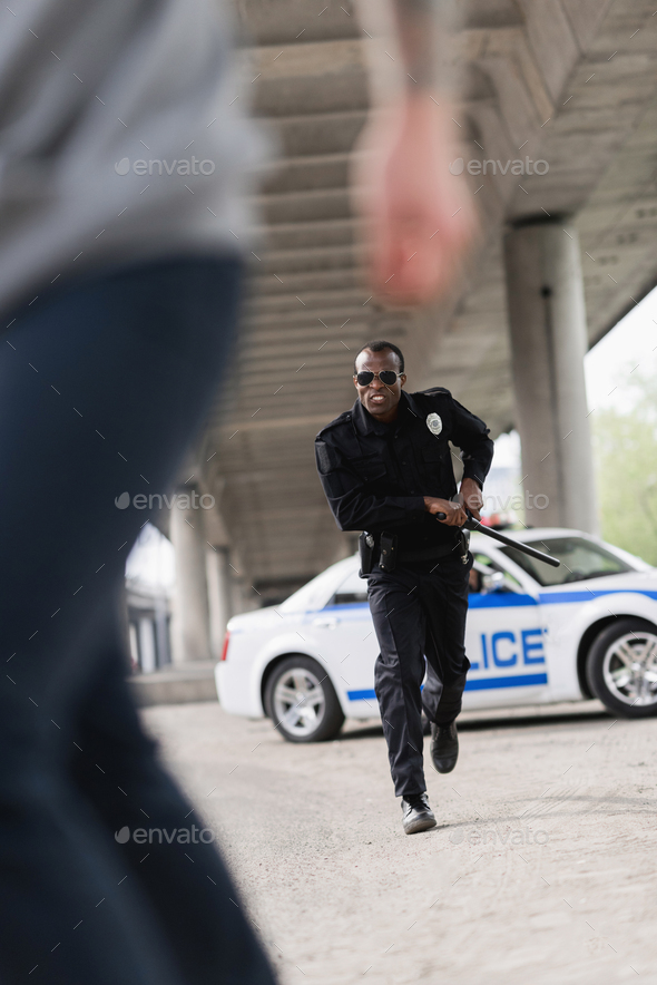 cropped shot of thief running from african american policeman