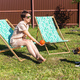 Young woman in pajama resting in chair on green lawn on sunny summer day and pet jack russell - PhotoDune Item for Sale