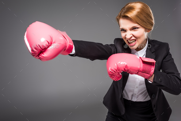 angry businesswoman in pink boxing gloves, isolated on grey