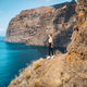 Independent relaxed calm slim girl tourist stands on the edge of a cliff with amazing ocean and sky - PhotoDune Item for Sale
