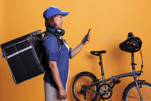 Slide view of takeaway delivery worker standing beside bike while checking directions