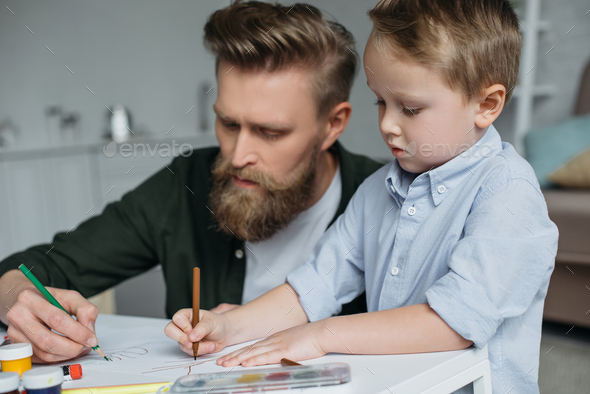 father and cute little son with colorful pencils drawing pictures together at home - Stock Photo - Images