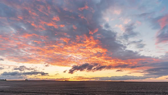 Colorful Golden Sunset with Stormy Clouds over Plowed Field on a Summer Evening