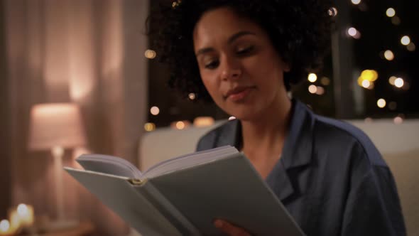 Happy Woman Reading Book Sitting in Bed at Night alt