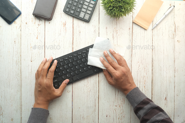  disinfecting keyboard with a white tissue on table