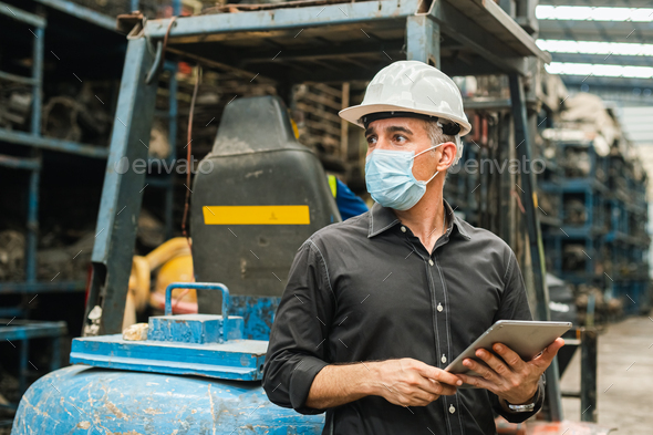 Man engineering worker wear protection face mask uniform and helmet holding tablet for work