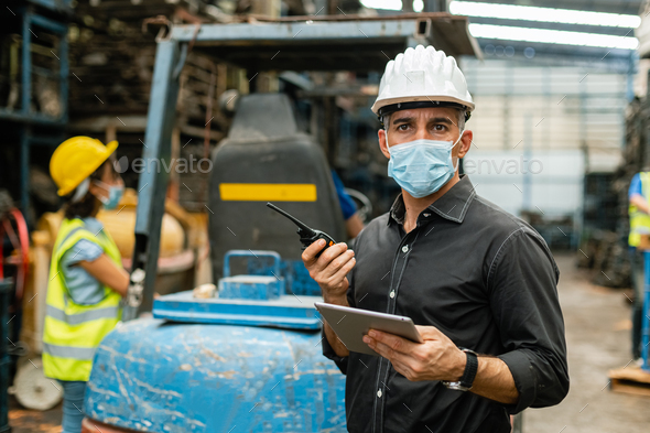man engineering worker wear protection face mask uniform and helmet tablet for work in warehouse.