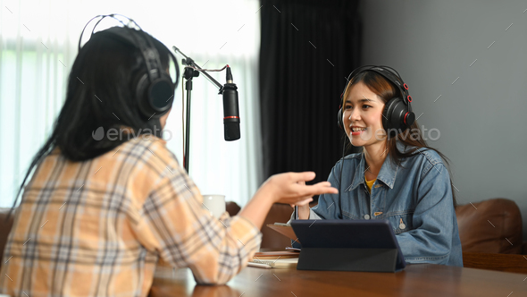 Smiling female radio host discussing various topics with her guest while streaming live audio.