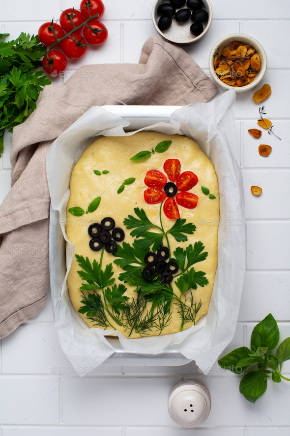 Raw focaccia creatively decorated with vegetables on parchment paper. Homemade flower focaccia. Sour