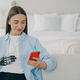 Disabled woman with phone holding glass of water with robotic arm prosthesis in bedroom. - PhotoDune Item for Sale