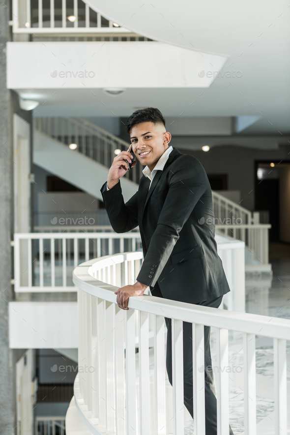 Smiling ethnic manager answering phone call on balcony