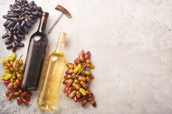 Two Wine bottles with grapes and wineglasses on old gray concrete table background with copy space.  - Stock Photo - Images