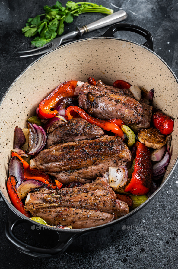 Braised slow cooked lamb shank in red wine sauce with vegetables in cooking pot. Black